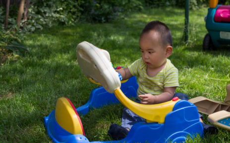 A little Chinese boy is playing toy on grassland in back yard.